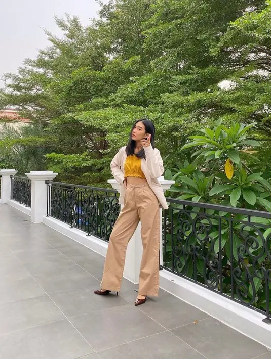Tampilan kekinian Alika Islamadina dengan kemeja putih sebagai outer dan bandeau top kuning mustard sebagai inner. Untuk bawahan, kamu bisa pilih high waist pants warna nude. (Instagram/alikaislamadina).