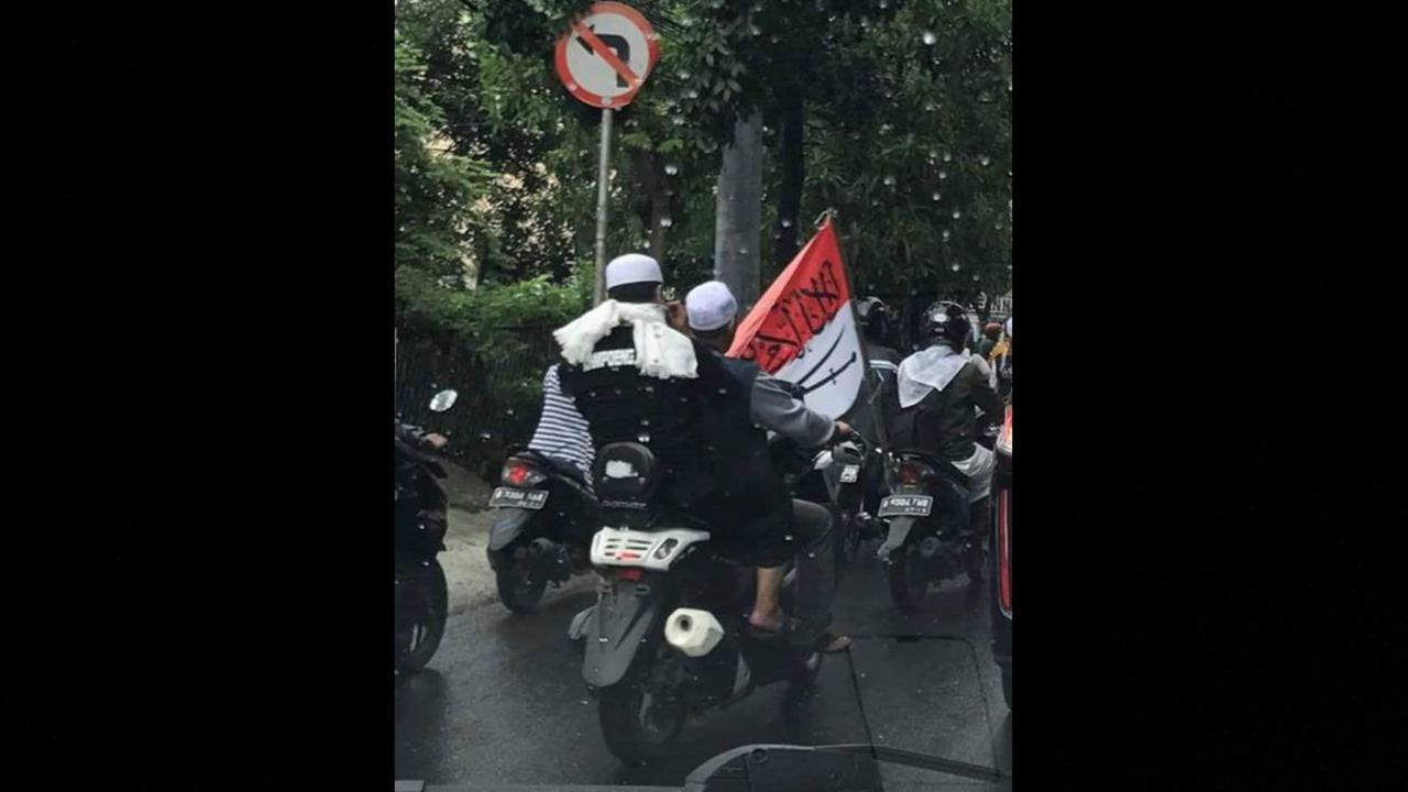 Bendera merah putih yang telah dicoret dengan tulisan Arab dan gambar silang pedang berwarna hitam.