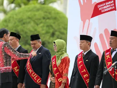 Presiden Joko Widodo (Jokowi) ketika memberikan Tanda Kehormatan Satyalencana Kebaktian Sosial kepada 893 orang yang telah melakukan 100 kali donor darah di Istana Bogor, Jawa Barat, Jumat (18/12). (Liputan6.com/Faizal Fanani)