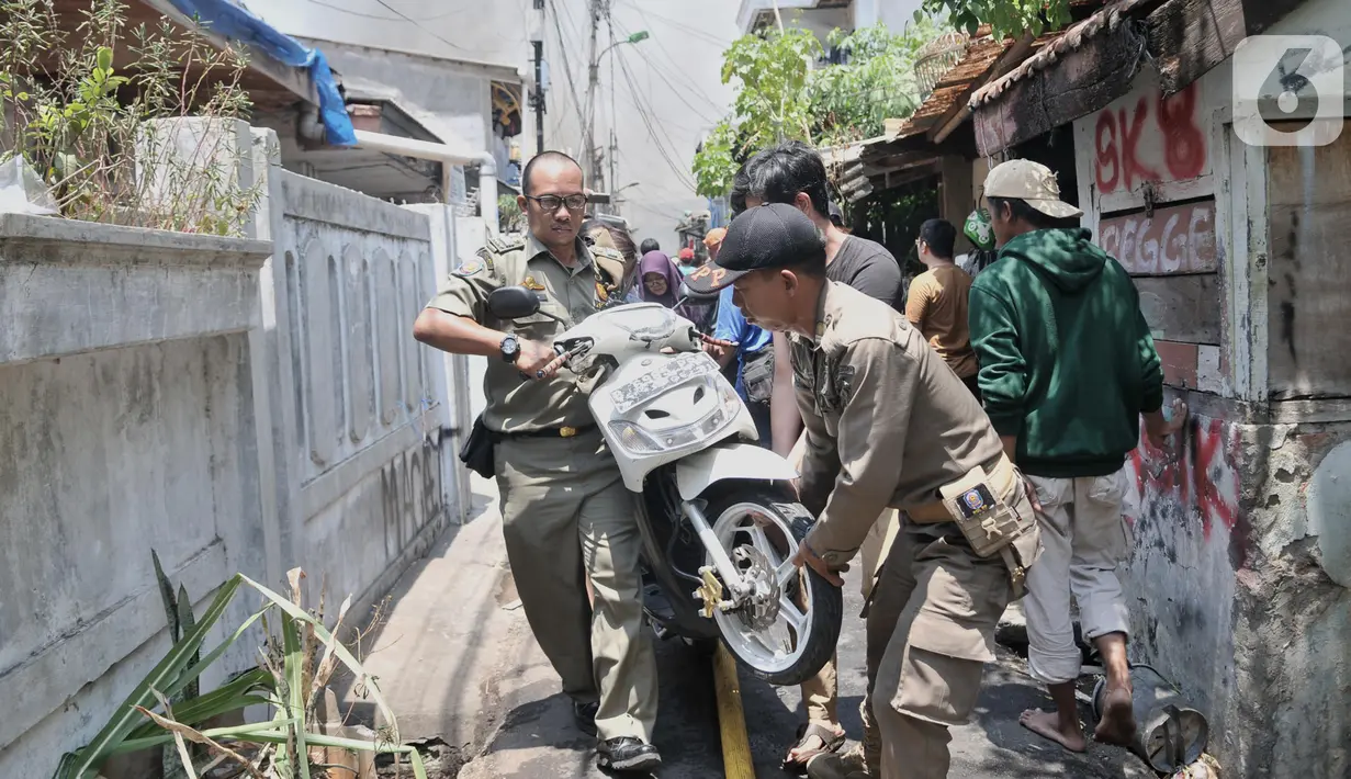 Petugas Satpol PP mengevakuasi sepeda motor milik warga saat kebakaran melanda permukiman di Jalan Kebon Jeruk 13, Taman Sari, Jakarta Barat, Minggu (6/10/2019). Kebakaran diduga akibat anak bermain korek api. (merdeka.com/Iqbal Nugroho)