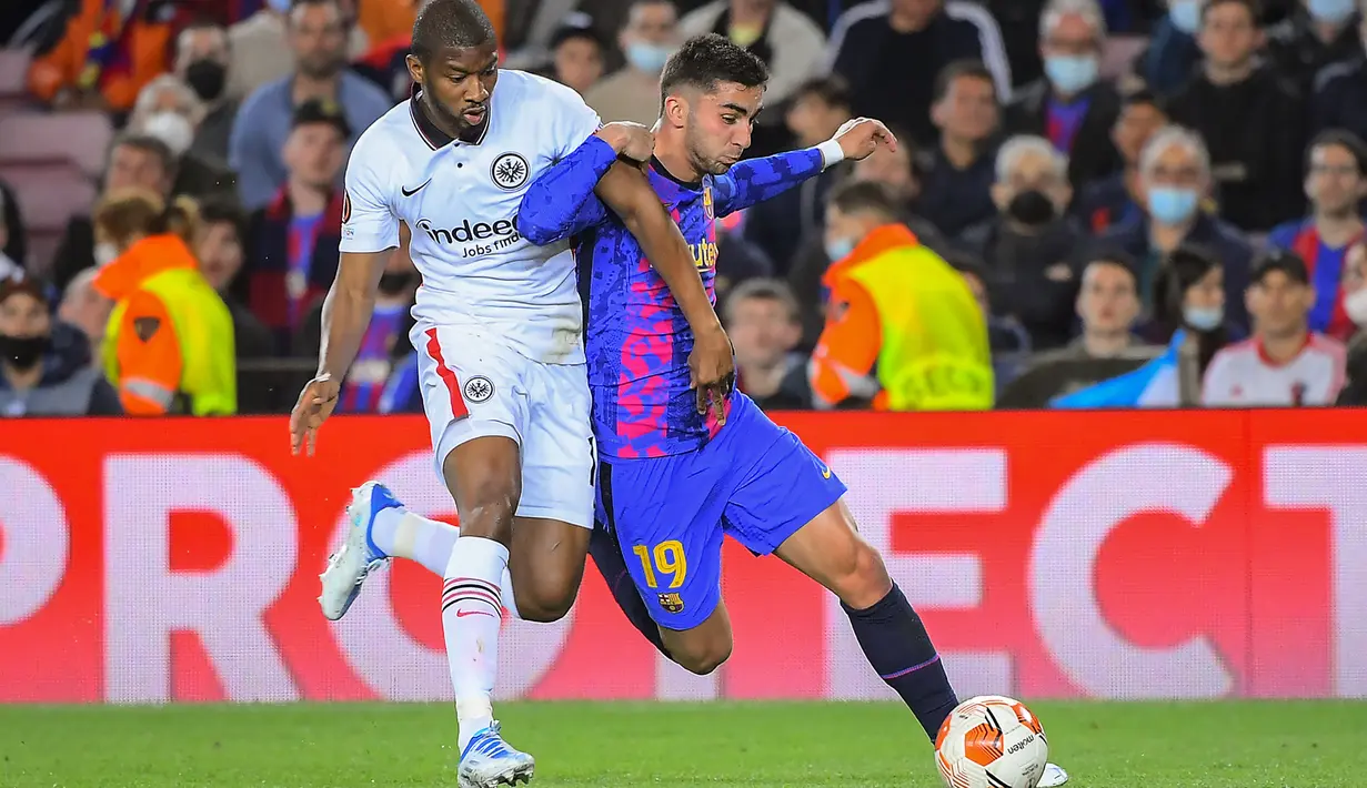 Bek Eintracht Frankfurt Almamy Toure (kiri) berebut bola dengan pemain depan Barcelona Ferran Torres pada leg 2 perempat final Liga Europa di Camp Nou, Jumat (15/4/2022). Barcelona secara mengejutkan kalah 2-3 dari Eintracht Frankfurt. (Jose Jordan / AFP)