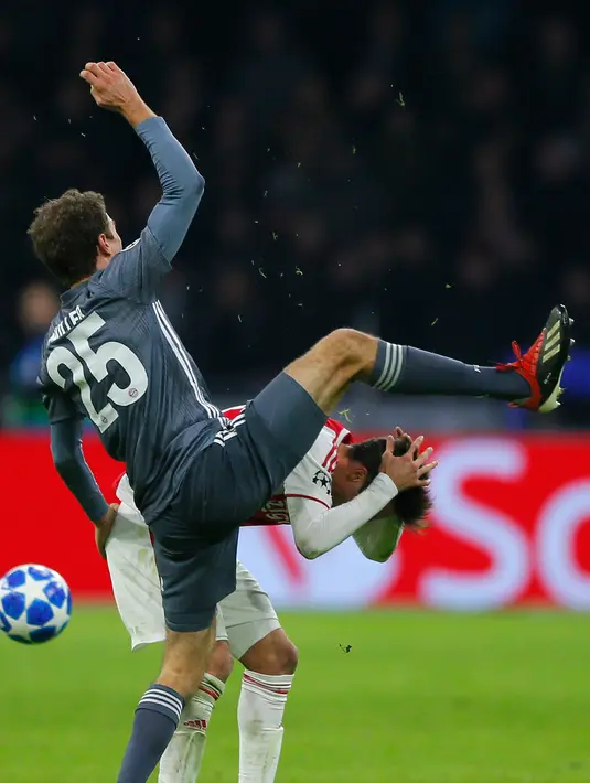 Gelandang Bayern Munchen Thomas Mueller menendang kepala bek Ajax Amsterdam Nicolas Tagliafico dalam laga Grup E Liga Champions di Amsterdam, Belanda, Rabu (12/12). Usai menendang Tagliafico, Muller menunjukkan gestur meminta maaf. (AP Photo/Peter Dejong)