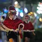 Seorang gadis kecil mengenakan kostum Sinterklas menikmati pemandangan dekorasi lampu Natal di tengah hujan rintik di sepanjang pusat perbelanjaan Orchard Road di Singapura (16/12/2020). Presiden Halimah Yacob telah menekan tombol sebagai tanda menyambut Natal 2020. (Xinhua/Then Chih Wey)
