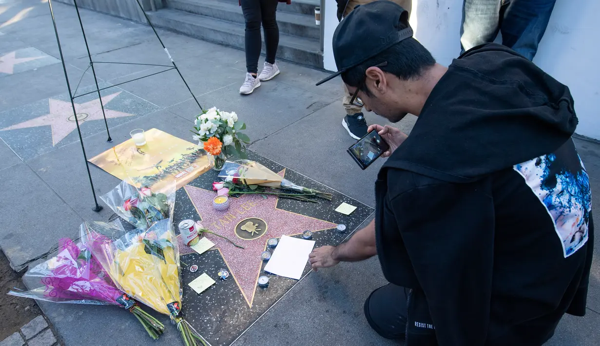 Penggemar mengambil gambar memorabilia yang diletakkan di atas bintang Walk of Fame milik pencipta sekaligus legenda komik-komik Marvel, Stan Lee di Hollywood, California, Senin (12/11). Stan Lee meninggal dunia pada usia 95. (VALERIE MACON / AFP)