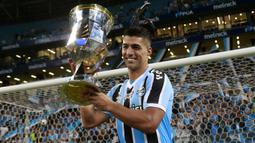 Selebrasi striker Gremio, Luis Suarez dengan trofi juara setelah mengalahkan Caxias pada laga leg kedua final Gaucho Championship di Arena do Gremio Stadium, Porto Alegre, Brasil (8/4/2023). Luis Suarez yang pernah menjadi rekan Lionel Messi di Barcelona saat ini tengah membela Gremio sejak Januari 2023 dan terikat kontrak hingga Desember 2024. Kembali bermain bersama Messi di Inter Miami tentu menjadi nostalgia indah bagi Luis Suarez. (AFP/Silvio Avila)