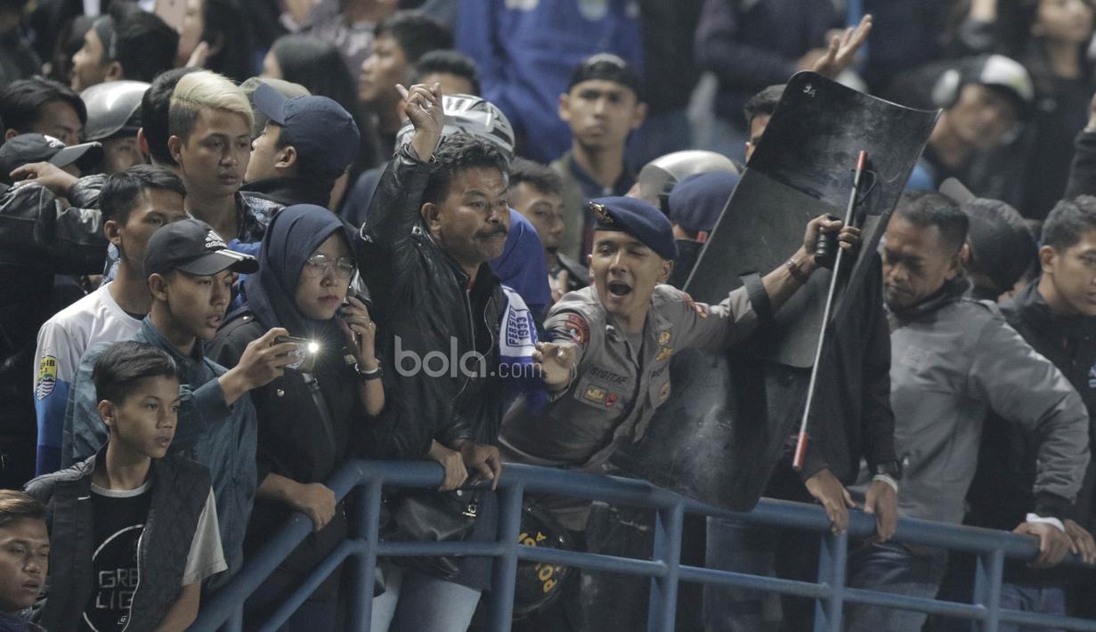 Seorang petugas kepolisian berusaha menahan emosi sejumlah bobotoh yang melakukan aksi protes kepada pemain PSM Makassar saat laga lanjutan Liga 1 di Stadion GBLA, Bandung, Rabu, (5/7/2017). (Bola.com/M Iqbal Ichsan)