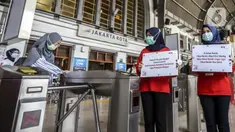 Petugas menunjukkan pesan peringatan COVID-19 di Stasiun Jakarta Kota, Jakarta, Rabu (28/10/2020). Mengantisipasi lonjakan penumpang saat cuti bersama dan Sumpah Pemuda, PT KCI mengajak pengguna KRL bersatu dan bangkit melawan COVID-19 dengan menerapkan 3M. (Liputan6.com/Johan Tallo)
