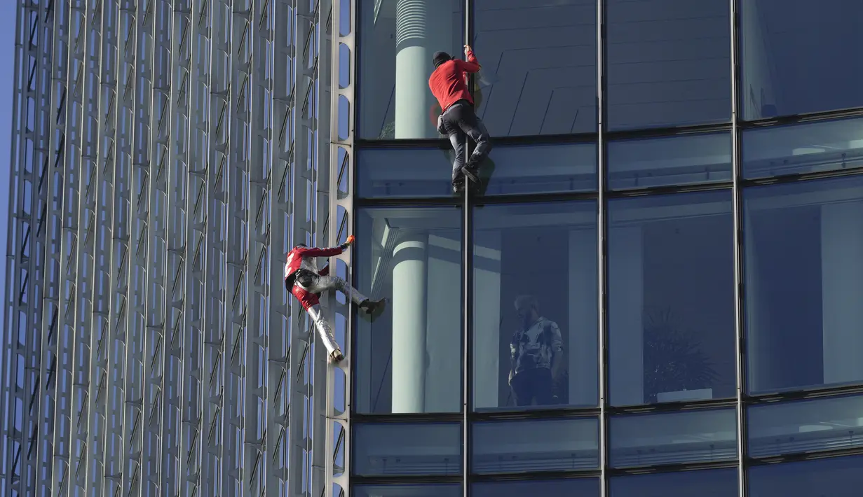 Alain Robert yang dikenal sebagai 'Spiderman Prancis' (kiri) dan Leo Urban memanjat gedung pencakar langit Skyper di pusat Frankfurt, Jerman, 23 November 2021. Alain Robert telah memanjat lebih dari 100 bangunan dalam 30 tahun karirnya dan ditangkap puluhan kali. (AP Photo/Michael Probst)