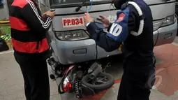 Warga mengambil gambar sepeda motor yang tertabrak Bus Transjakarta di kawasan permata hijau, Jakarta, Jumat (27/3/2015). Sejumlah warga sedang melakukan evakuasi speda motor yang berada di dalam bus transjakarta. (Liputan6.com/Johan Tallo)