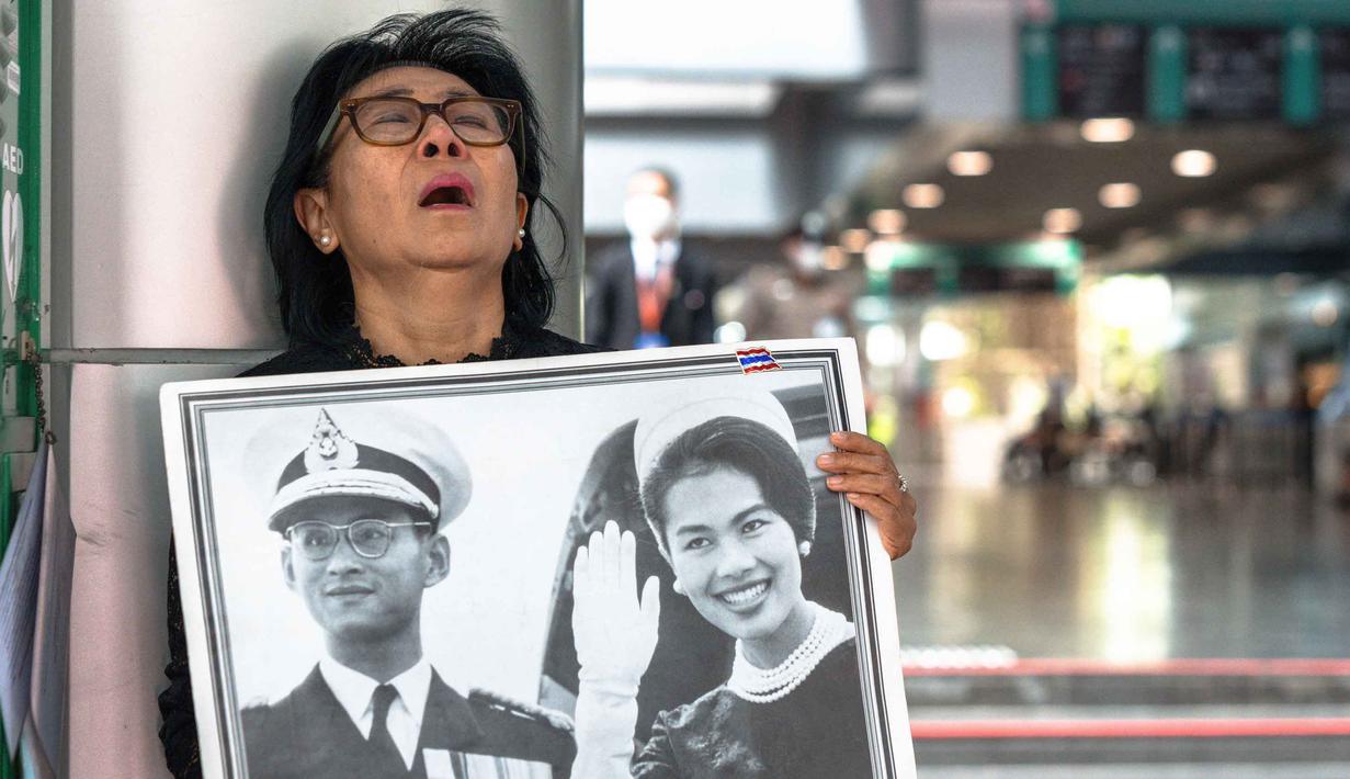 Seorang pelayat Thailand, Kanjana Malaithong, memegang potret Ratu Thailand yang telah wafat, Sirikit Kitiyakara, dan Raja Thailand Bhumibol Adulyadej, sambil menangis di Rumah Sakit Chulalongkorn di Bangkok pada 25 Oktober 2025. (Chanakarn Laosarakham/AFP)