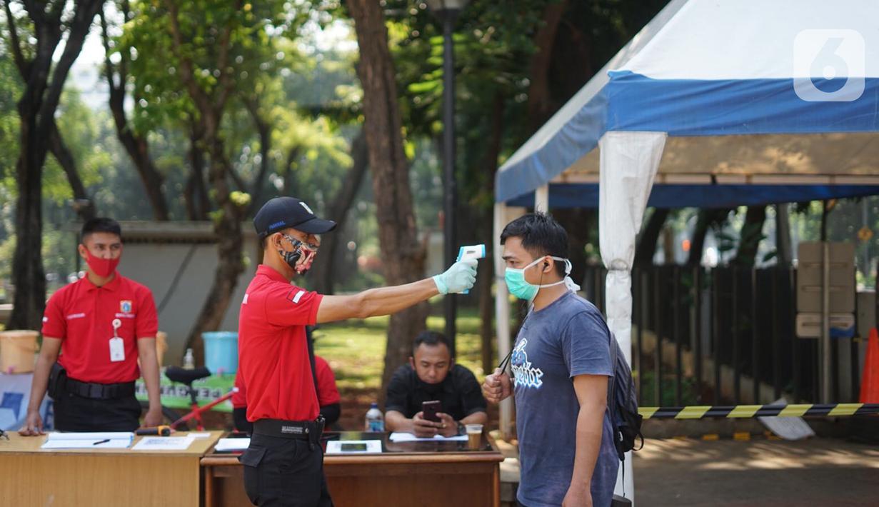 Petugas mengecek suhu tubuh warga di sekitar Taman Lapangan Banteng, Jakarta Pusat, Sabtu (13/6/2020). Mulai hari ini, Taman Lapangan Banteng kembali dibuka untuk umum namun jumlah pengunjung tetap dibatasi sebanyak 200 orang setiap pagi dan sore hari. (Liputan6.com/Immanuel Antonius)