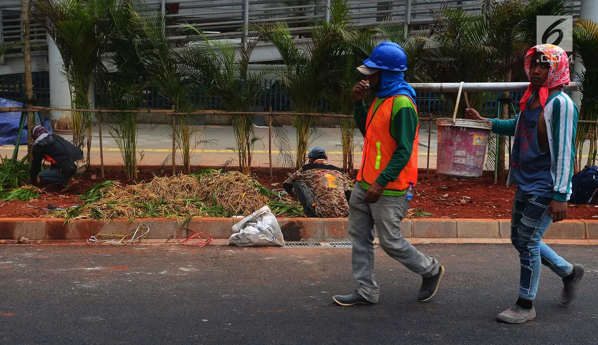 Pekerja melintasi dekat penataan jalur pedestrian di sepanjang Jalan Jenderal Sudirman - Jalan MH Thamrin, Jakarta, Selasa (10/7). Gubernur DKI Anies Baswedan menyatakan pelebaran trotoar itu  akan rampung Juli ini. (Merdeka.com/Imam Buhori)