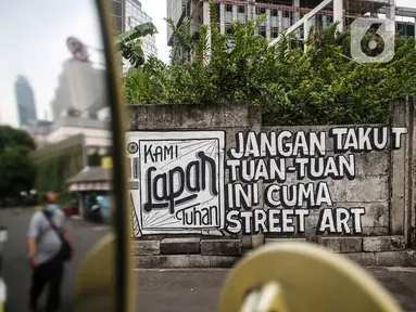 Mural yang bertuliskan “Kami Lapar Tuhan” di kawasan Jakarta Pusat, Selasa (24/8/2021). Banyak beberapa tempat mural yang menyuarakan kebebasan berpendapat saat ini menjadi viral lantaran dihapus oleh petugas. (Liputan6.com/Johan Tallo)