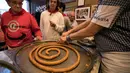 Karyawan memotong-motong donat khas Spanyol atau churros di restoran dessert tradisional La Manueta, Pamplona, Spanyol, Rabu (10/7/2019). Jika dulu hanya dikenal dengan rasa manis setelah digoreng, saat ini churros memiliki topping yang lebih beraneka ragam. (JAIME REINA/AFP)