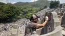 Seorang pria melukis ulang nama yang pudar di makam kerabat selama festival Qingming di pemakaman di Hong Kong (5/4). Biasanya warga cenderung membuat persembahan untuk keluarga atau kerabat mereka agar tetap nyaman di akhirat. (AFP Photo/Isaac Lawrence)