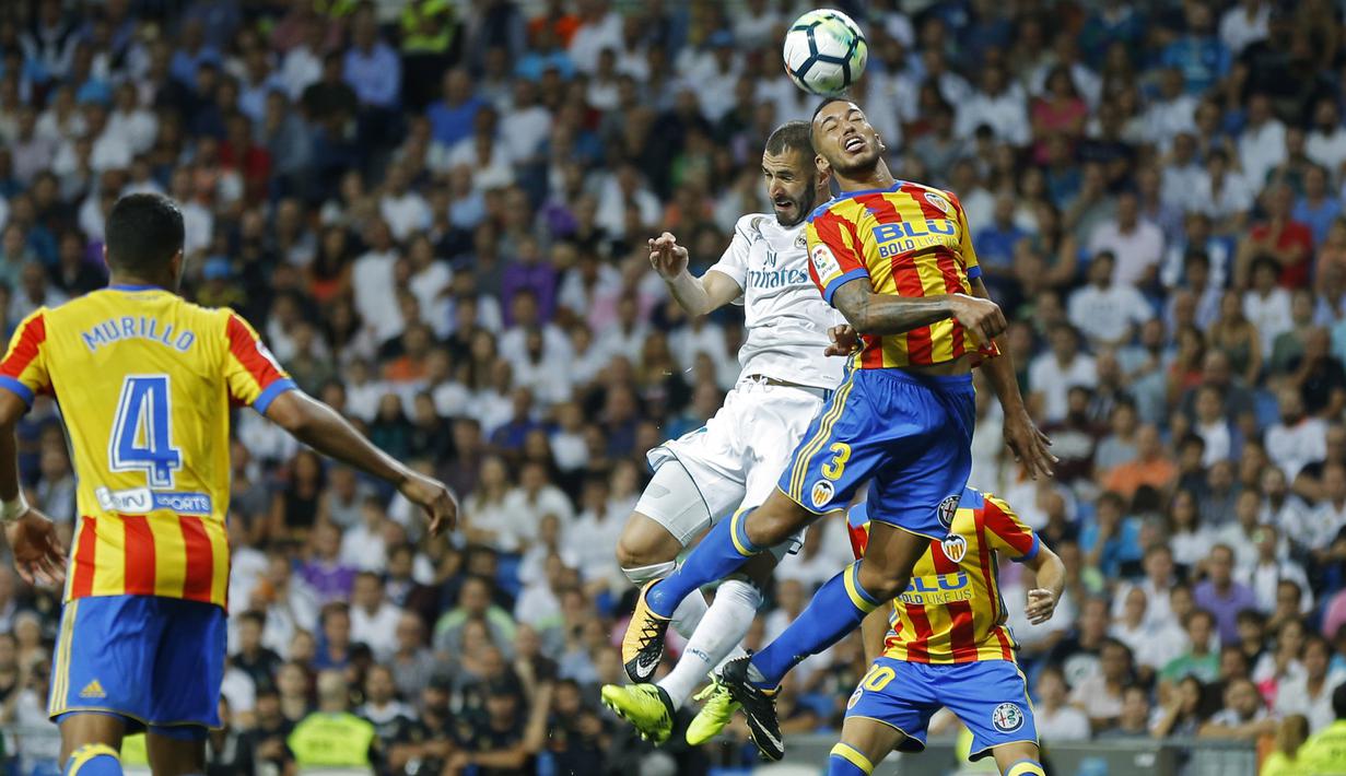Pemain Real Madrid, Karim Benzema (kiri) atas) menyundul bola saat duel dengan pemain Valencia, Ruben Vezo pada lanjutan La Liga Spanyol di Santiago Bernabeu stadium, Madrid, (27/8/2017). Real ditahan Imbang 2-2. (AP/Francisco Seco)