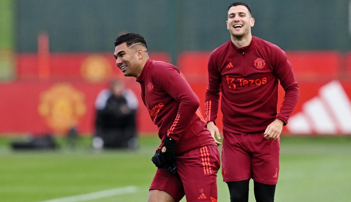 Pemain Manchester United, Casemiro dan Diogo Dalot, tampak semringah saat sesi latihan di Carrington Training Complex, Senin (23/10/2023). Mereka tampak bercanda dan tertawa bersama di sesi latihan. (AFP/Paul Ellis)