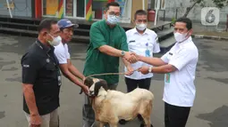 Corporate Secretary Division Head SCM Grup Gilang Iskandar (kemeja hijau) menyerahkan hewan kurban secara simbolis di studio 5 Indosiar, Daan Mogot, Jakarta, Rabu (6/7/2022). PT SCM menyerahkan sejumlah hewan kurban kepada masyarakat jelang Hari Raya Idul Adha ada 65 hewan kurban yang diserahkan SCM tahun ini. (Liputan6.com/Angga Yuniar)
