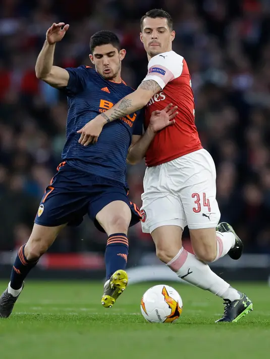 Gelandang Arsenal, Granit Xhaka berebut bola dengan pemain Valencia, Goncalo Guedes dalam leg pertama semifinal Liga Europa di Emirates Stadium, Jumat (3/5/2019). Sempat tertinggal, Arsenal berhasil mengalahkan tamunya, Valencia dengan skor 3-1. (AP/Kirsty Wigglesworth)