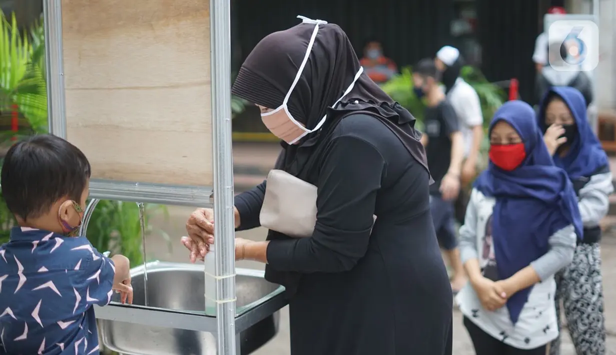 Pengunjung mencuci tangan saat masuk ke kawasan Pasar Minggu, Jakarta, Selasa (23/6/2020). Pascapenutupan tiga hari terkait ditemukannya tiga pedagang yang positif COVID-19, pengunjung Pasar Minggu kini diwajibkan mencuci tangan dan cek suhu tubuh. (Liputan6.com/Immanuel Antonius)