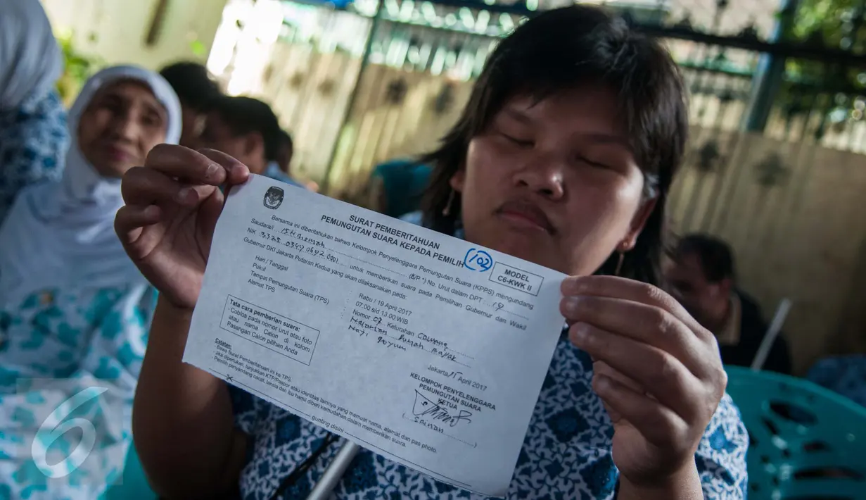 Seorang wanita menunjukan lembaran data pemilih saat akan menggunakan hak pilihya dalam Pilkada Putaran kedua di TPS 07 Kelurahan Cawang, Jakarta, Rabu (19/4). (Liputan6.com/Gempur M. Surya)