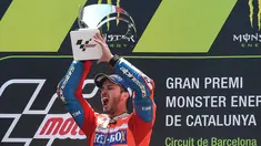 Pembalap Ducati, Andrea Dovizioso mengangkat trofi di podium setelah memenangi MotoGP Catalunya di sirkuit Barcelona Catalunya, Minggu (11/6). Dovizioso berhasil menyelesaikan balapan dengan catatan waktu tercepat 44 menit 41,518 detik. (Josep LAGO/AFP)