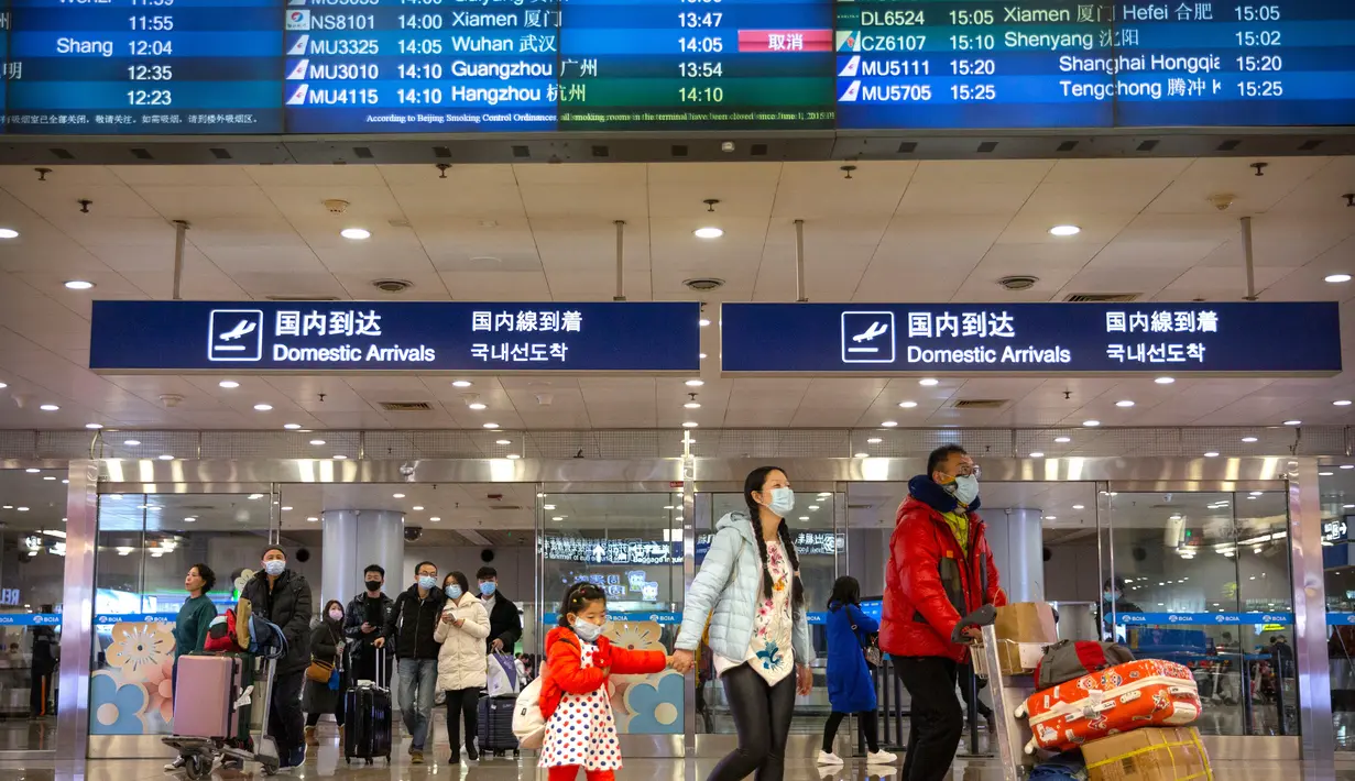 Pelancong berjalan melintasi papan informasi yang menunjukkan penerbangan dari Wuhan telah dibatalkan di Bandara Internasional Ibu Kota Beijing pada Kamis (23/1/2020). China menangguhkan semua transportasi dari dan ke kota Wuhan, yang merupakan pusat penyebaran virus korona. (AP/Mark Schiefelbein)