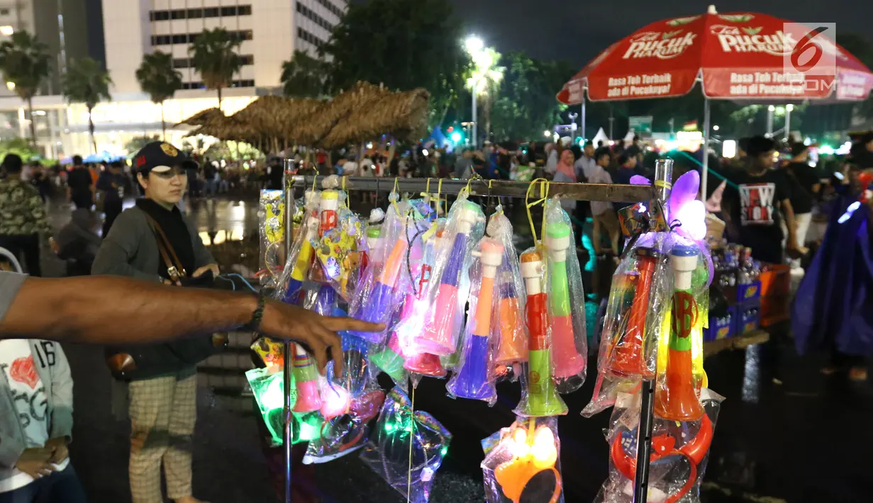 Pedagang menjual terompet pada malam pergantian tahun di kawasan Bundaran HI, Jakarta, Senin (31/12). Pergantian tahun dimanfaatkan pedagang untuk mencari keuntungan dengan berjualan pernak pernik tahun baru.(Liputan6.com/Angga Yuniar)