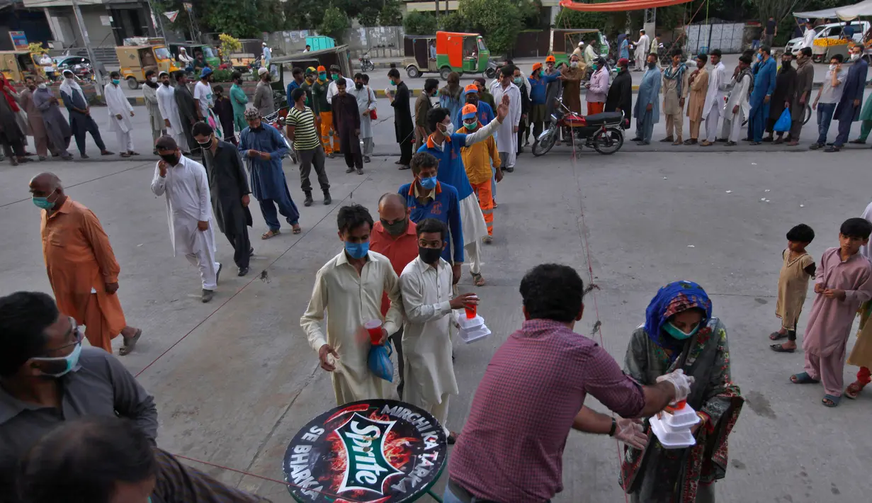 Orang-orang menerima kotak makanan dan minuman manis tradisional untuk berbuka puasa di Rawalpindi, Pakistan, Minggu, (3/5/2020). Umat Muslim di seluruh dunia sedang melaksanakan Ramadan untuk menahan diri dari makan, minum sejak subuh sampai senja. (AP/Anjum Naveed)