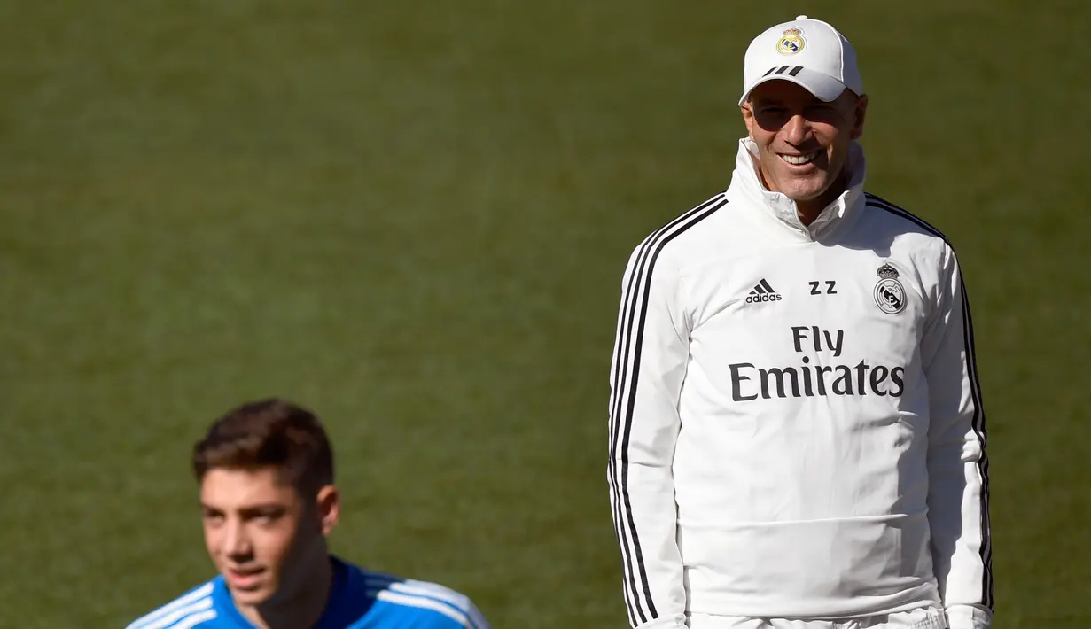 Pelatih Real Madrid Zinedine Zidane tersenyum saat menghadiri sesi pelatihan di fasilitas pelatihan Valdebebas di Madrid (15/3). Real Madrid akan bertanding melawan Celta Vigo pada lanjutan La Liga Spanyol. (AFP Photo/Gabriel Bouys)