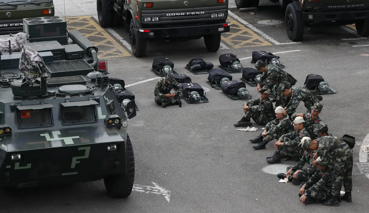 Polisi paramiliter China duduk di dekat kendaraan lapis baja di stadiun olahraga di Shenzhen, kota di dekat perbatasan dengan Hong Kong, China (30/10/2019). Ratusan polisi militer China ini dikhawatirkan Amerika Serikat akan dikirim ke Hong Kong untuk membubarkan pengunjuk rasa. (AP Photo/Andy Wong)