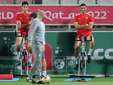 Pelatih Maroko, Walid Reragui (tengah) berbicara dengan bek Achraf Hakimi (kanan) dan Nayef Aguerd selama sesi latihan di Stadion Al Duhail SC di Doha (16/12/2022). Maroko akan bertanding melawan Kroasia untuk memperebutkan juara 3 Piala Dunia 2022. Keduanya dipertemukan kembali setelah pernah bertanding pada babak penyisihan grup F lalu. (AFP/Karim Jafaar)