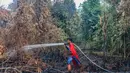 Pelajar bernama Rudiansyah dengan mengenakan kostum Superman membantu memadamkan kebakaran hutan dan lahan di Petuk Katimpun, Palangkaraya, Kalimantan Tengah, 17 Agustus 2026. (AFP/ Reina)