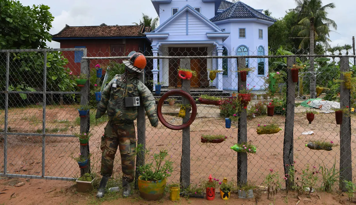 Orang-orangan sawah diikat ke pagar di depan sebuah rumah di provinsi Kampong Cham, Kamboja, 11 Oktober 2020. Para petani di desa itu menggunakan orang-orangan sawah atau disebut juga Tim Mong untuk menangkal virus corona  Covid-19 berdasarkan kepercayaan yang mereka yakini. (TANG CHHIN Sothy/AFP)