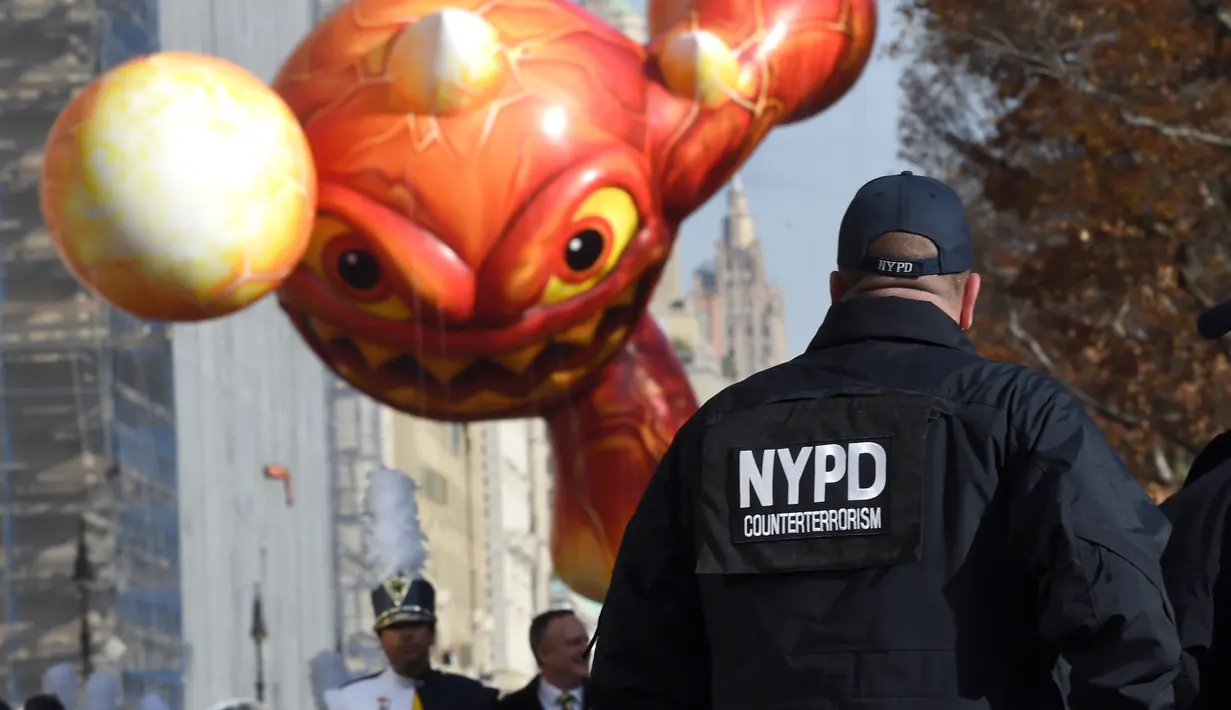 Petugas Kepolisian Kota New York mengawasi mengawasi Parade Thanksgiving Day di New York City (26/11/2015). Beragam balon raksaksa yang dibuat seperti tokoh animasi menjadi suguhan utama dalam perayaan tersebut. (AFP Photo/Timothy A. Clary)