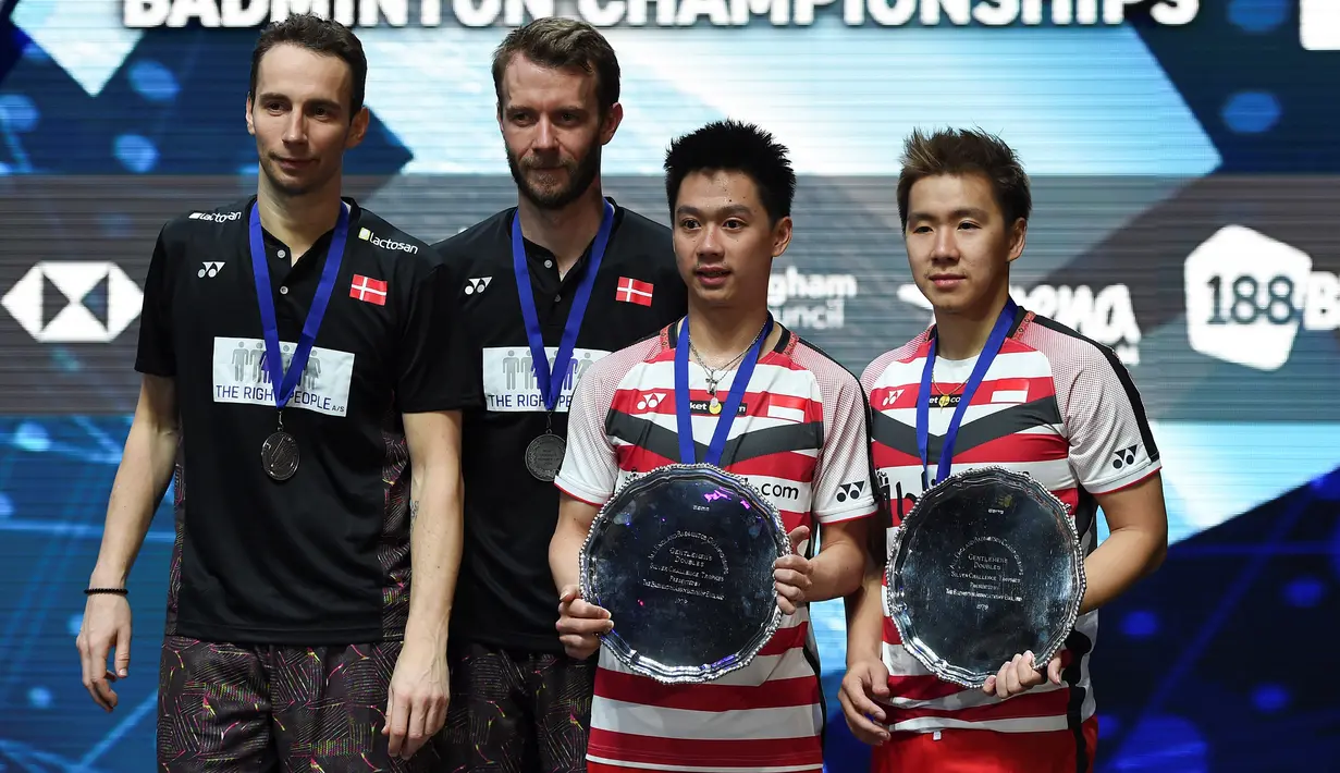 Ganda putra Indonesia, Kevin Sanjaya (kedua kanan) dan Marcus Fernaldi (kanan) berpose sambil memegang piala usai mengalahkan pebulutangkis Denmark Mathias Boe dan Carsten Mogensen di final All England, Birmingham, Inggris (18/3). (AFP Photo/Paul Ellis)