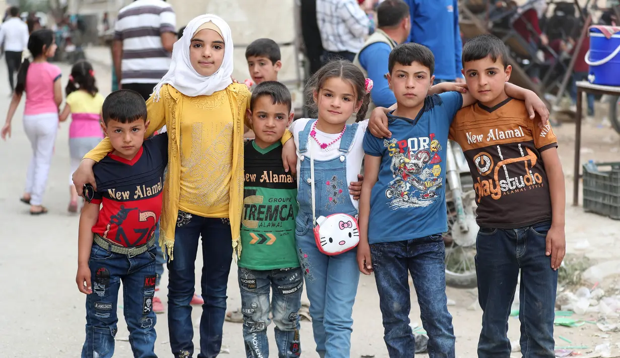 Anak-anak Suriah foto bersama di taman bermain sementara merayakan Idul Fitri, hari libur Muslim yang dimulai pada akhir bulan puasa Ramadhan, di Ariha di provinsi Idlib yang dikuasai pemberontak barat laut Suriah, (26/5/2020). (AFP Photo/Omar Haj Kadour)