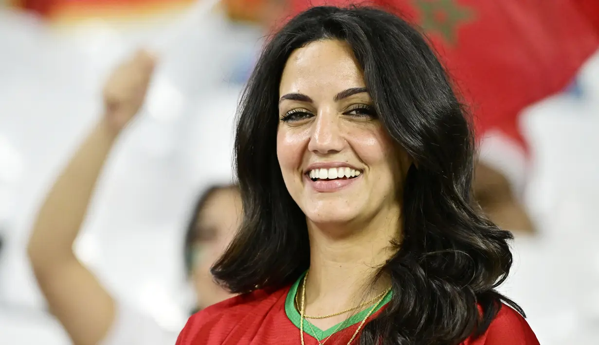 Fans Maroko tersenyum saat menyaksikan laga Maroko melawan Spanyol pada laga Piala Dunia 2022 di Stadion Education City, Selasa (6/12/2022). (AFP/Javier Soriano)