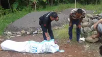 Petugas tengah melakukan pemeriksaan jenazah dalam karung di pantai Cibalong, pantai selatan, Garut (Liputan6.com/Jayadi Supriadin)