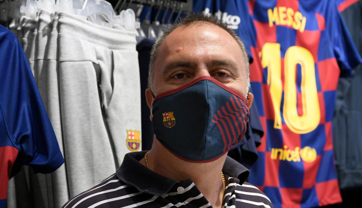 Fans memakai masker berlogo Barcelona di Toko Asesoris Barcelona, Senin (25/5/2020). Di tengah pandemi virus Corona, Barcelona menjual masker dengan harga 18 euro atau sekitar Rp 291 ribu. (AFP/Lluis Gene)