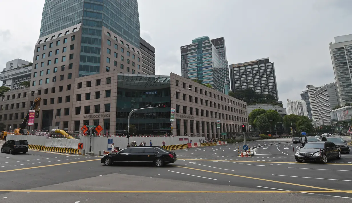Iring-iringan mobil yang diyakini membawa pemimpin Korea Utara Kim Jong-un melewati Orchard Road menuju St Regis Hotel di Singapura, Minggu (10/6). Kedatangan Kim menjelang pertemuan bersejarah dengan Donald Trump pada Selasa mendatang. (AP/Joseph Nair)
