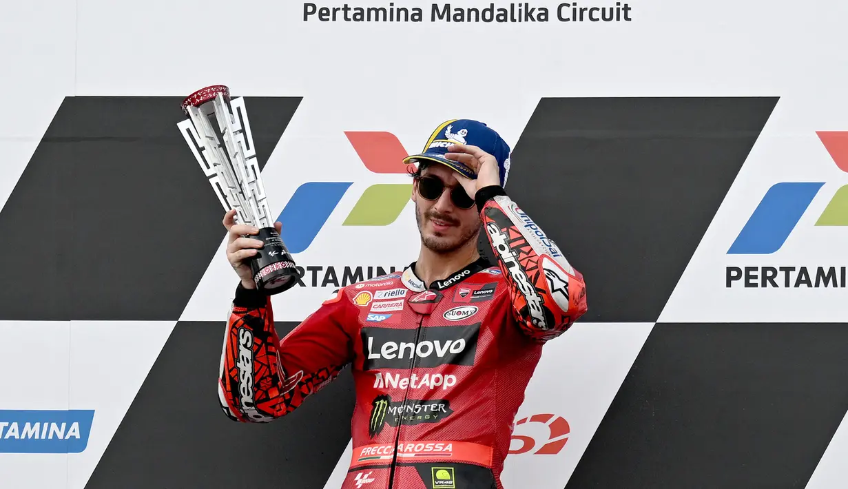 Pembalap Ducati Lenovo, Francesco Bagnaia memegang trofi kemenangan di atas podium MotoGP Indonesia 2023 di Sirkuit Mandalika, Lombok, NTB, Minggu (15/10/2023). Bagnaia kembali memuncaki klasemen MotoGP 2023. Ia sempat tergeser di posisi kedua setelah Jorge Martin memenangkan Sprint Race pada Sabtu (14/10/2023). (AFP/Sonny Tumbaleka)