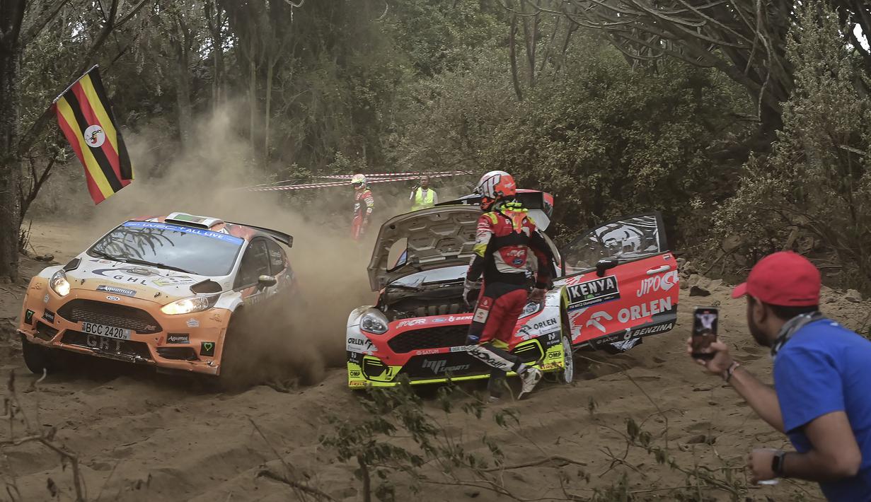 Tim reli Zambia, Leroy Gomes dan Urshlla Gomes (kiri) menggunakan mobil Ford Fiesta melewati tim reli Republik Ceska, Martin Prokop dan Zdenek Jurka yang mogok dalam ajang Safari Rally Kenya 2022 yang berlangsung di kota tepi danau Naivasha pada 24 Juni 2022. (AFP/Tony Karumba)