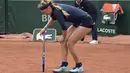Victoria Azarenka menahan sakit di lututnya saat bertanding melawan petenis Italia, Karin Knapp, pada babak pertama Prancis Terbuka 2016 di Roland Garros, Paris, (24/5/2016). (AFP/Eric Feferberg)