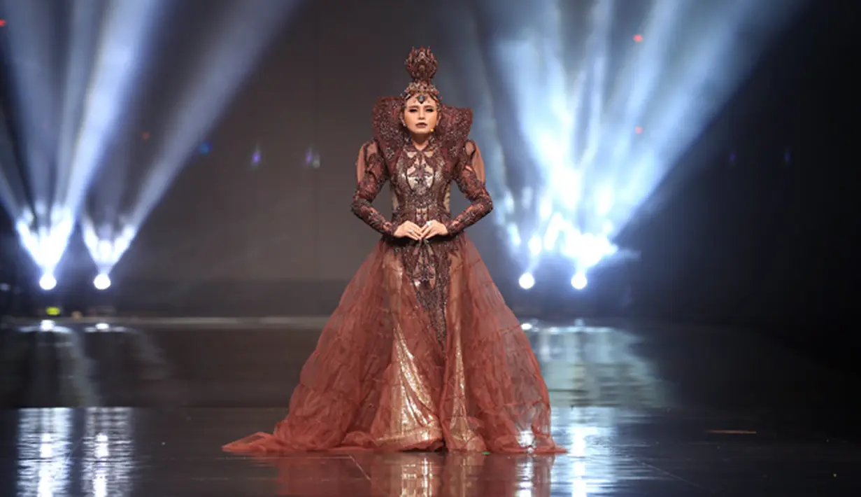 Berbalut dengan gaun panjang berwarna merah, di bagian lehernya yang tinggi dan menutupi sebagian kepalanya. Untuk hiasan kepala yang dikenakannya juga sangat mewah dan berhasil menarik perhatian. (Deki Prayoga/Bintang.com)