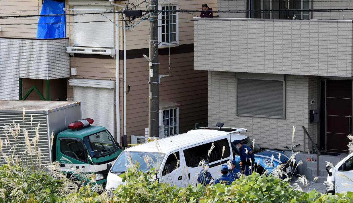 Seorang pria berada di samping rumah yang ditutupi kain biru di mana polisi menemukan sembilan mayat termasuk dua kepala yang disimpan di kotak pendingin di Zama, Prefektur Kanagawa, Jepang, (31/10). (AFP Photo/Toru Yamanaka)