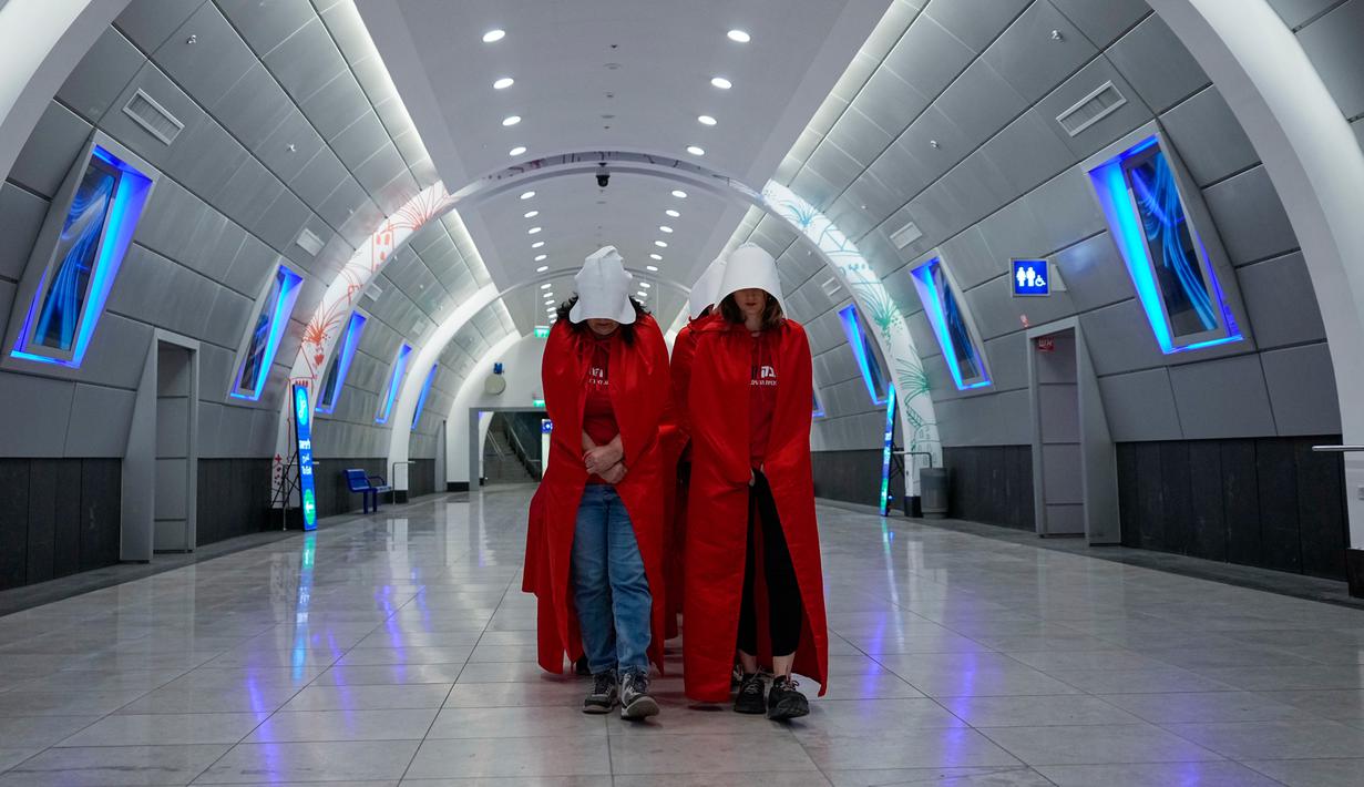 Pengunjuk rasa yang mendukung hak-hak perempuan berpakaian seperti karakter dari serial TV "The Handmaid's Tale" saat melakukan perjalanan untuk memprotes rencana pemerintah baru Perdana Menteri Benjamin Netanyahu untuk merombak sistem peradilan di sebuah stasiun kereta api di Yerusalem, Israel, 1 Maret 2023. Mengacu pada fenomena yang berkembang, harian Inggris The Guardian menggambarkan penampilan para pelayan sebagai salah satu simbol paling kuat dari protes feminis kontemporer. (AP Photo/Ohad Zwigenberg)