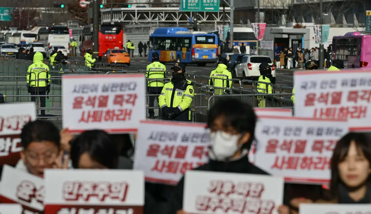 Dengan penjagaan ketat pihak kepolisian setempat, pengunjuk rasa turun ke jalan untuk menuntut mundur Presiden Korea Selatan Yoon Suk Yeol pasca-pencabutan status darurat militer. (ANTHONY WALLACE/AFP)