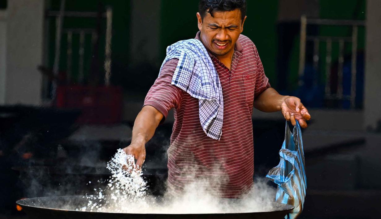 Bagi warga Aceh, kuah Beulangong merupakan hidangan primadona untuk berbuka puasa, sering kali dimasak di masjid atau meunasah untuk dinikmati bersama. Tampak dalam foto, seorang pria memasak hidangan kari tradisional yang disebut 'kuah beulangong' untuk dibagikan saat berbuka puasa, sekaligus memperingati turunnya Al-Quran selama bulan suci Ramadan, di Banda Aceh pada Sabtu 7 Maret 2026. (CHAIDEER MAHYUDDIN/AFP)