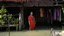 Zuriah berdiri di luar rumahnya yang terendam banjir di Mondoliko, Jawa Tengah, Indonesia, 1 Agustus 2022. Karena tidak mampu untuk pindah ke rumah baru, Zuriah tetap tinggal di rumah itu meski hampir semua tetangganya pindah. (AP Photo/Dita Alangkara)